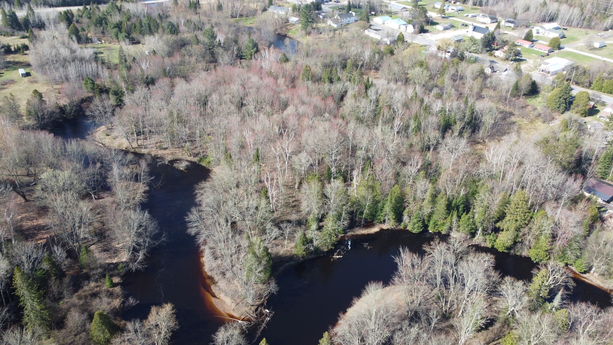 Drone view of wooded acreage with water and an aeiral view of Germfask MI