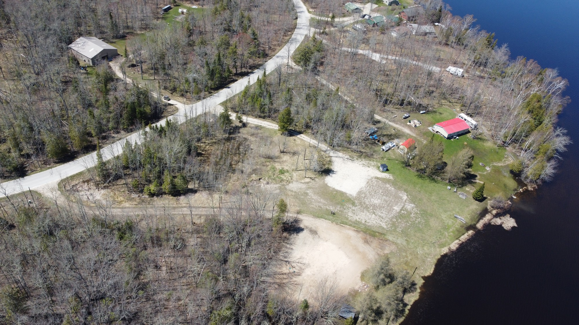 Aerial view of a waterfront property with road access and open yard